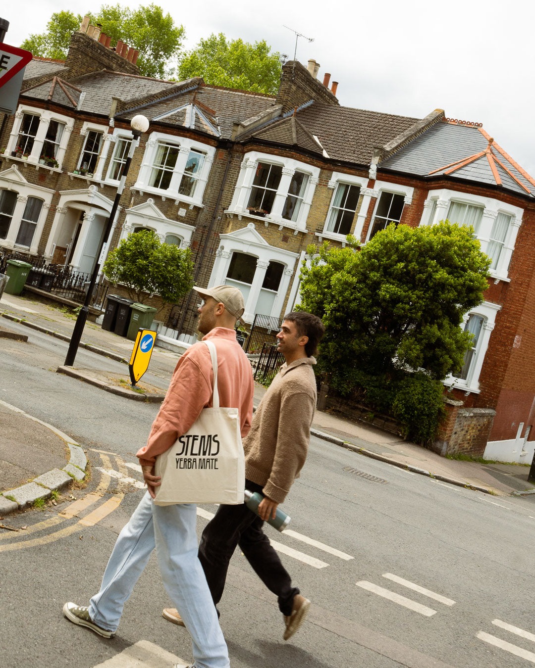 Two people crossing a London street carrying Stems tote bags