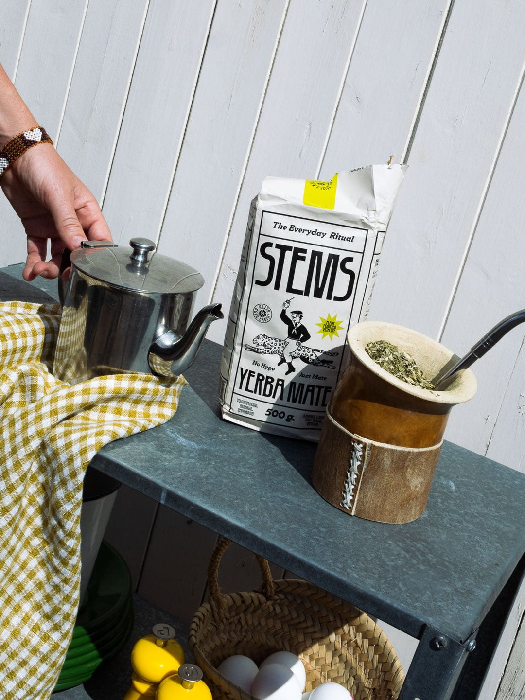 A teapot, a Stems carton and a gourd on a garden table