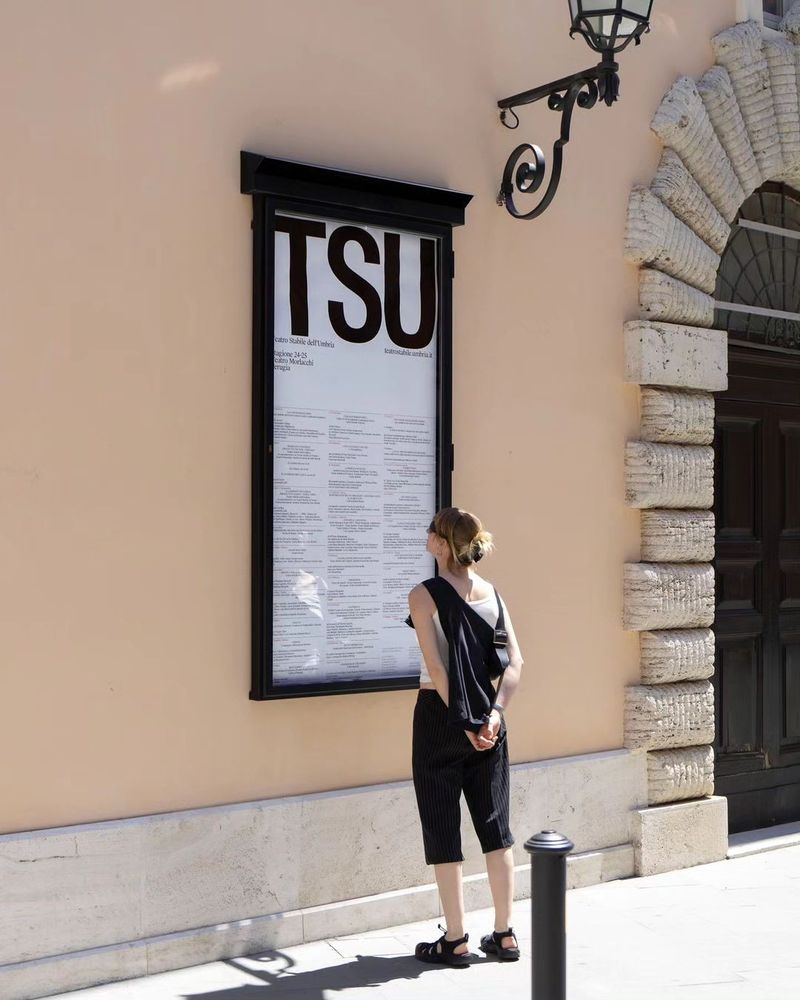 Teatro Stabile dell’Umbria identity by Due Studio: A theatre identity built on tall condensed TSU initials, shown in a real street poster case in Perugia; black on white, institutional rather than loud