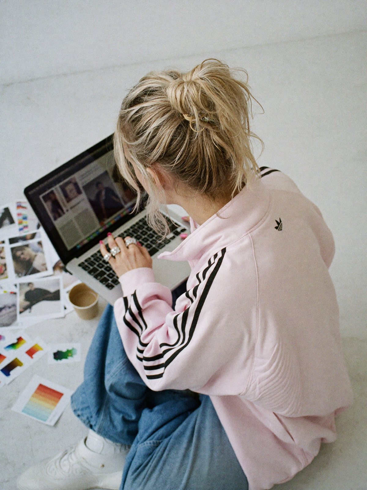 Sophie Evans working on a laptop on the studio floor, surrounded by printed layouts and colour swatches