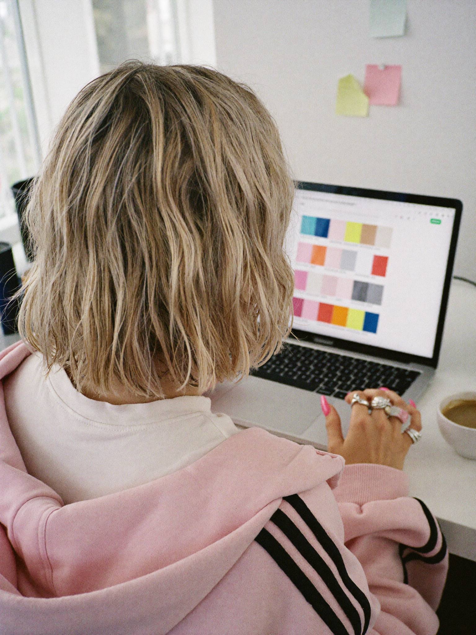 From behind: Sophie Evans at her laptop with a grid of colour swatches on screen