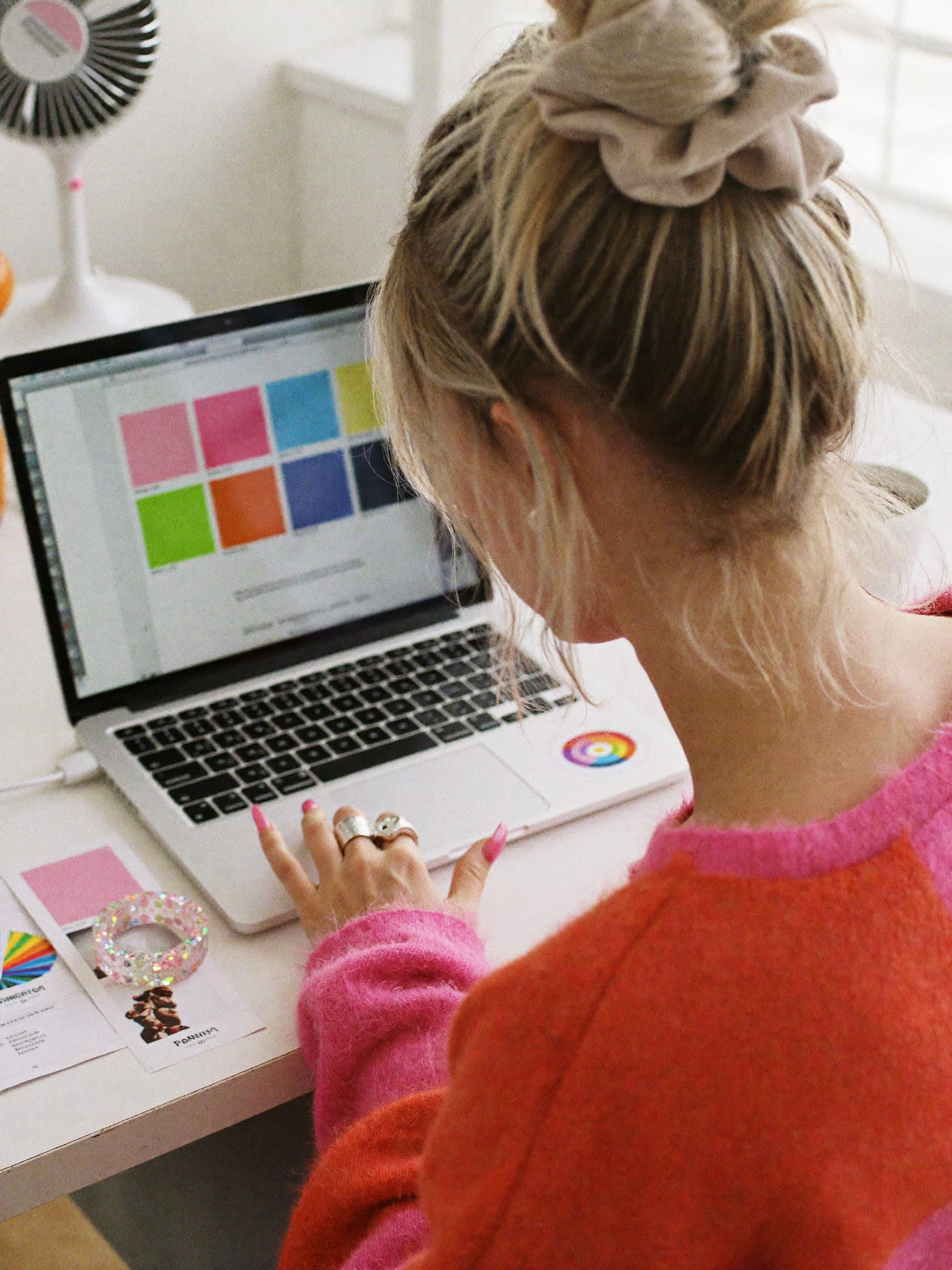 Over the shoulder of Sophie Evans choosing colours, swatches beside her laptop